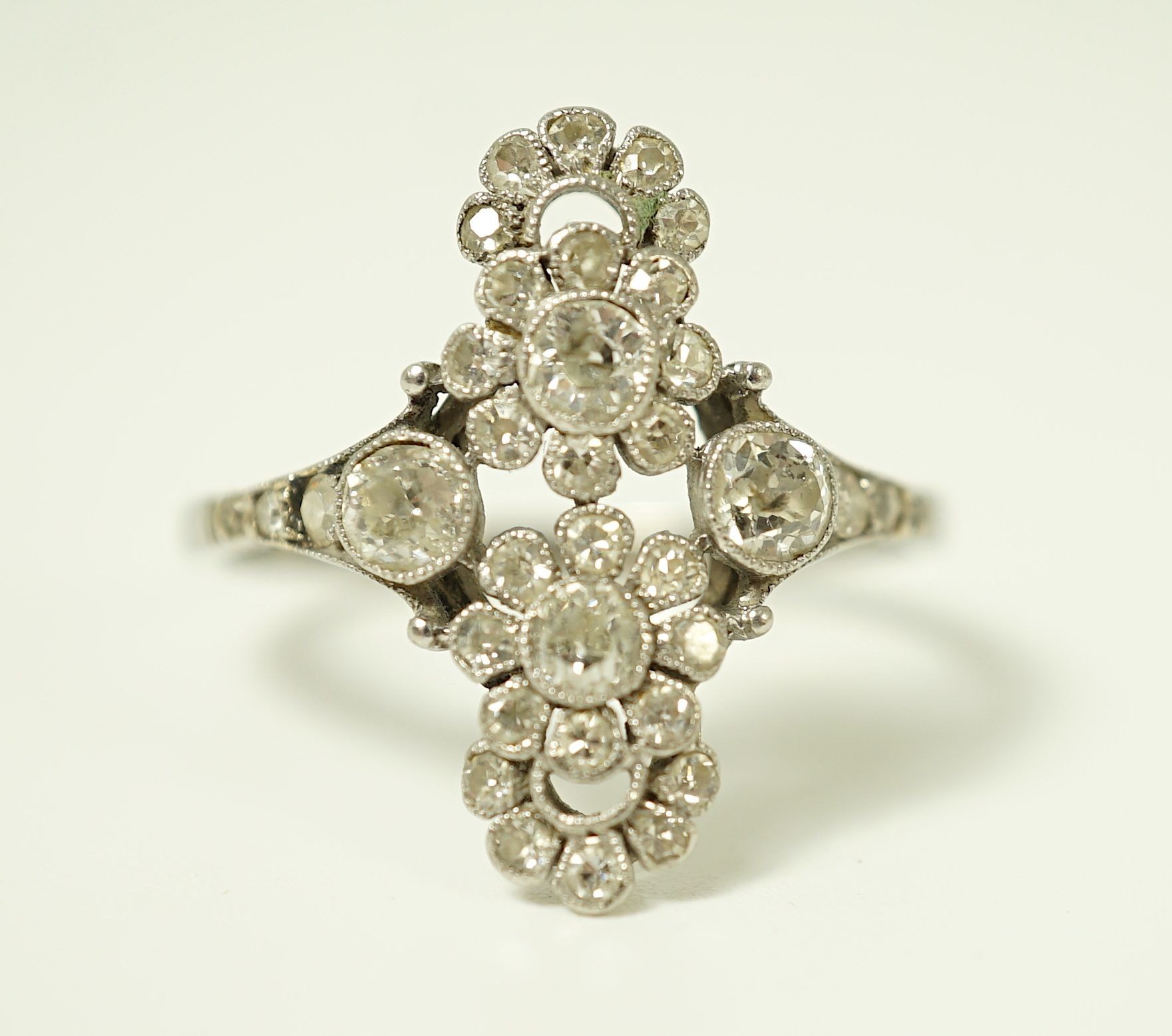 A 1920's platinum and millegrain diamond set flower head cluster upfinger ring